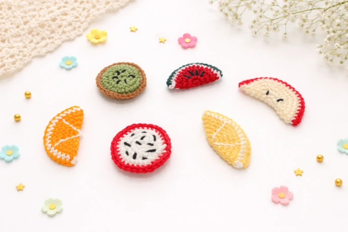 Crocheted slice fruit set of sliced up orange, dragonfruit, kiwi, watermelon, apple and lemon, surrounded by light decorations